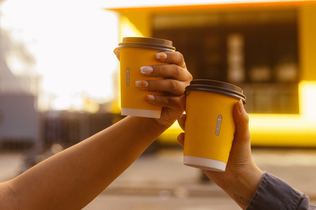 Two hands holding two yellow cups
