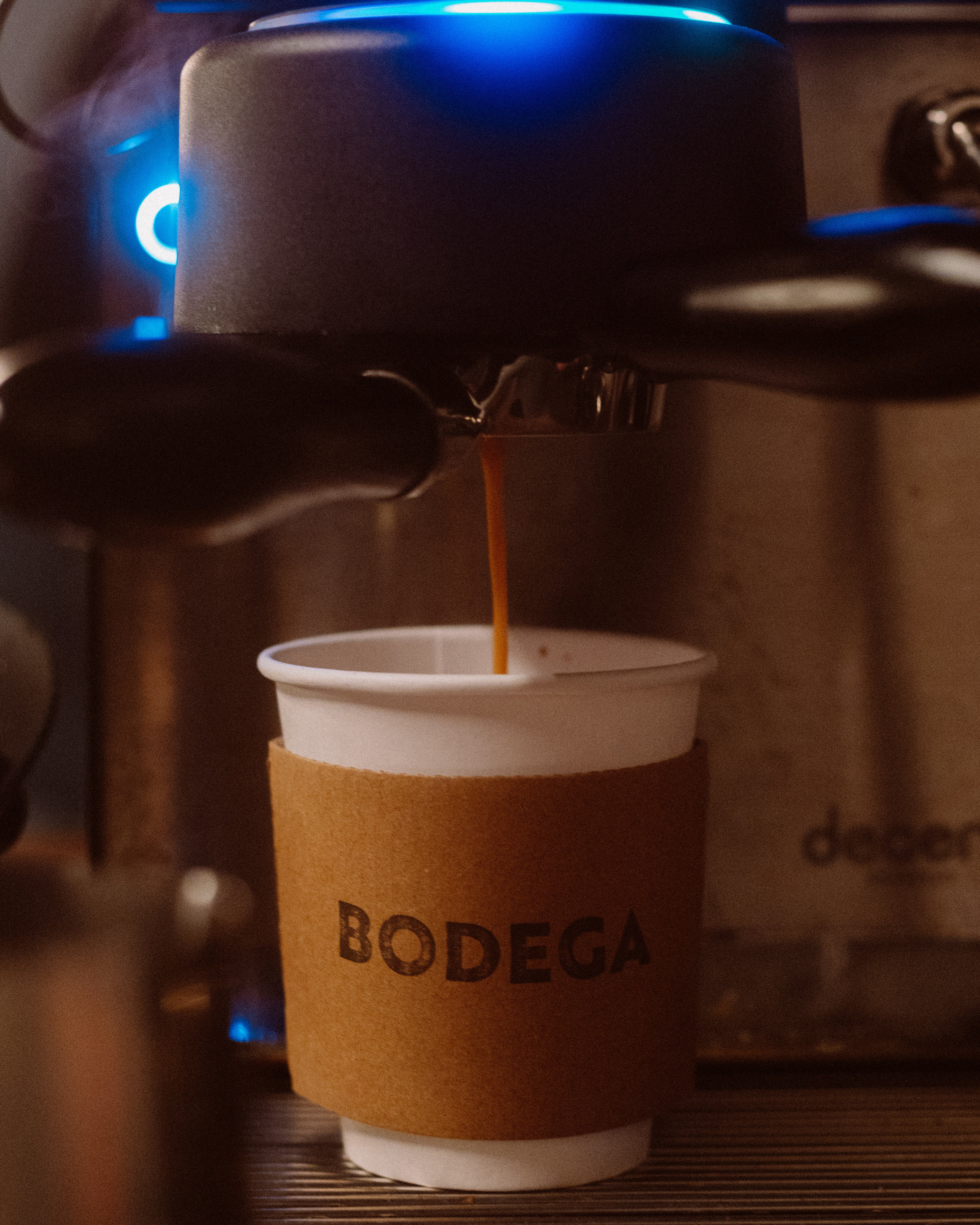 An espresso shot being pulled into a cupp with a sleeve that says BODEGA - Bodega Coffee Roasters