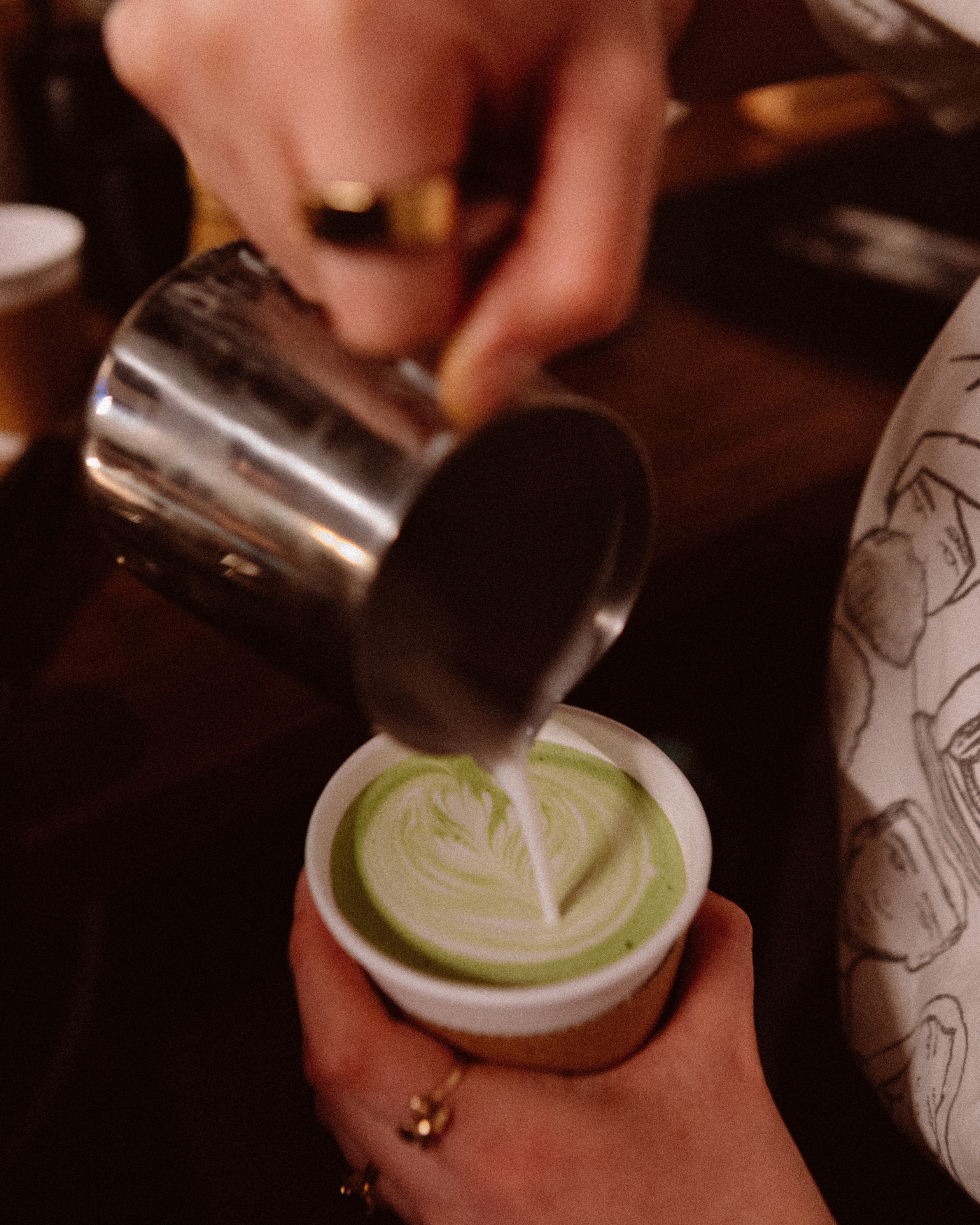 Milk being pour into a cup with matcha. - Bodega Coffee Roasters
