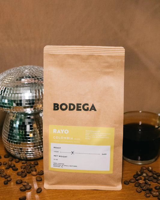 Bodega coffee package with coffee beans and a glass of coffee on a wooden surface